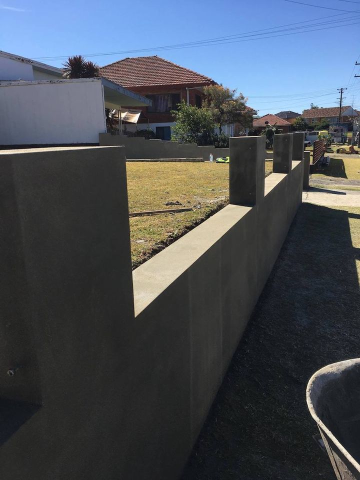 A long rendered boundary wall running the length of a driveway