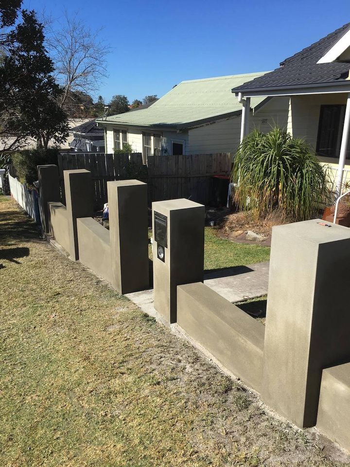A rendered front fence with square piers and a built in letterbox, on a suburban street