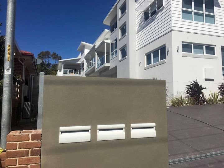 A rendered pier holding three letterbox slots in front of the same unit block