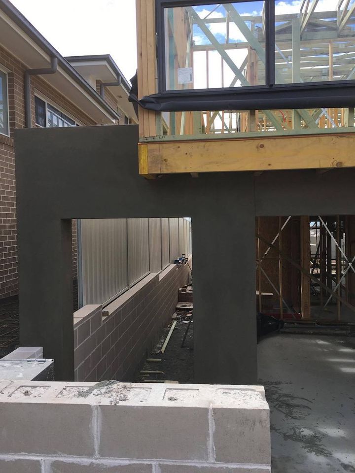 A rendered opening beneath a first floor addition, with the block base still exposed