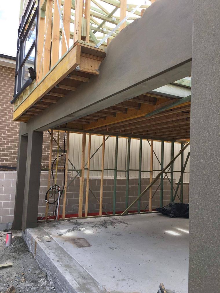 The same wall after rendering, with square columns and a flat grey finish