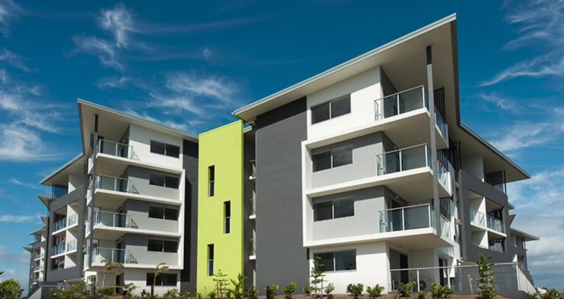 A four storey apartment block rendered in white, grey and green