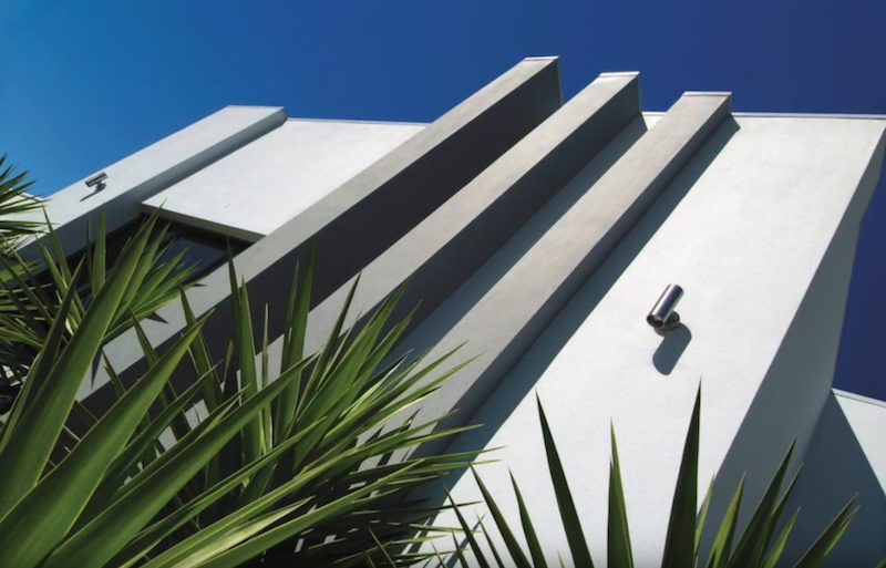 A modern rendered facade of angled white and charcoal fins against a deep blue sky
