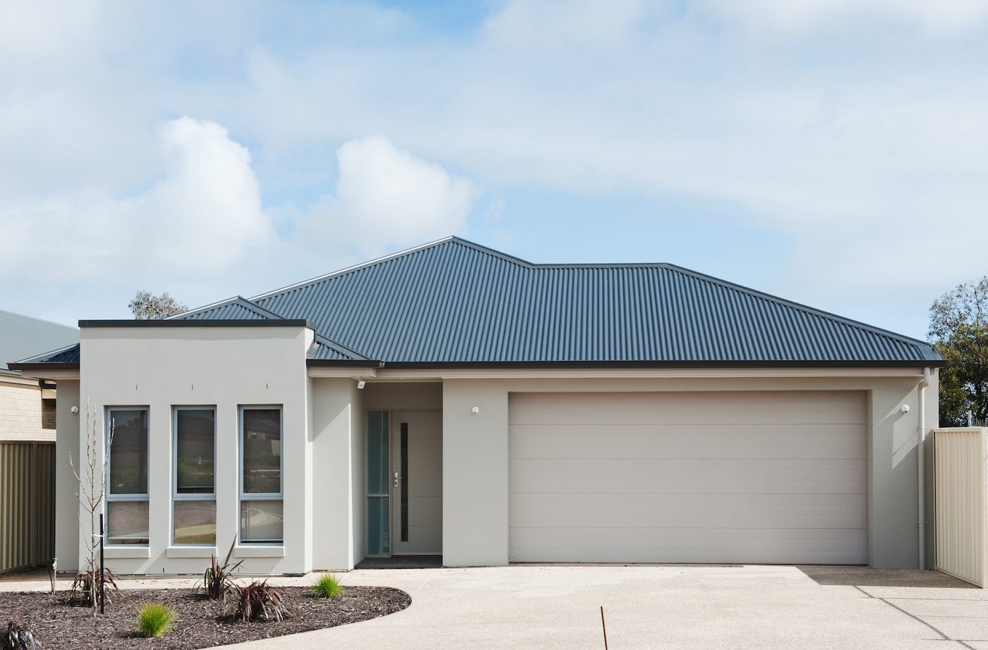 A rendered single storey home with a tiled roof, double garage and finished driveway