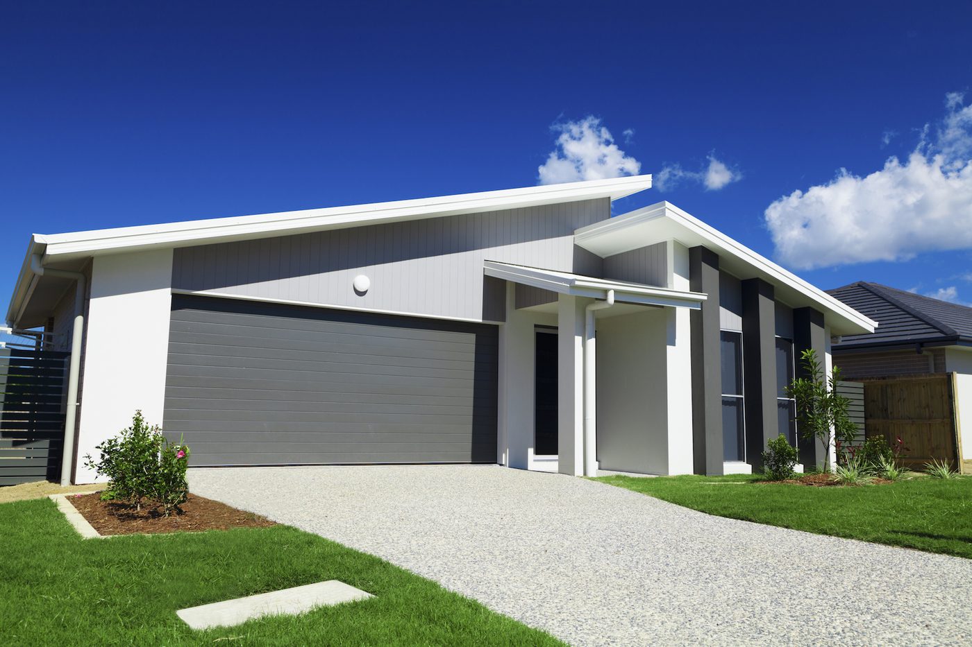 A newly rendered single storey home with a dark garage door and freshly laid lawn